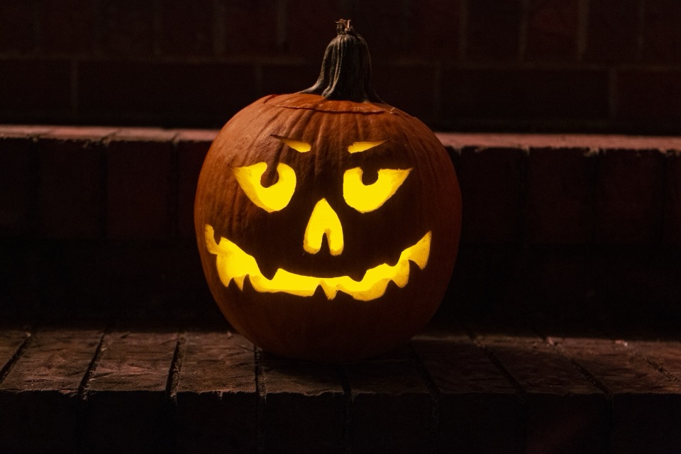 A carved jack-o'-lantern glowing on dark brick steps at night